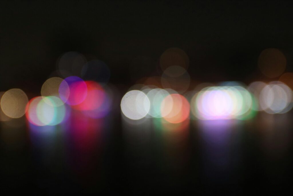 Vibrant and colorful bokeh lights defocused against a dark night background, creating an abstract visual.